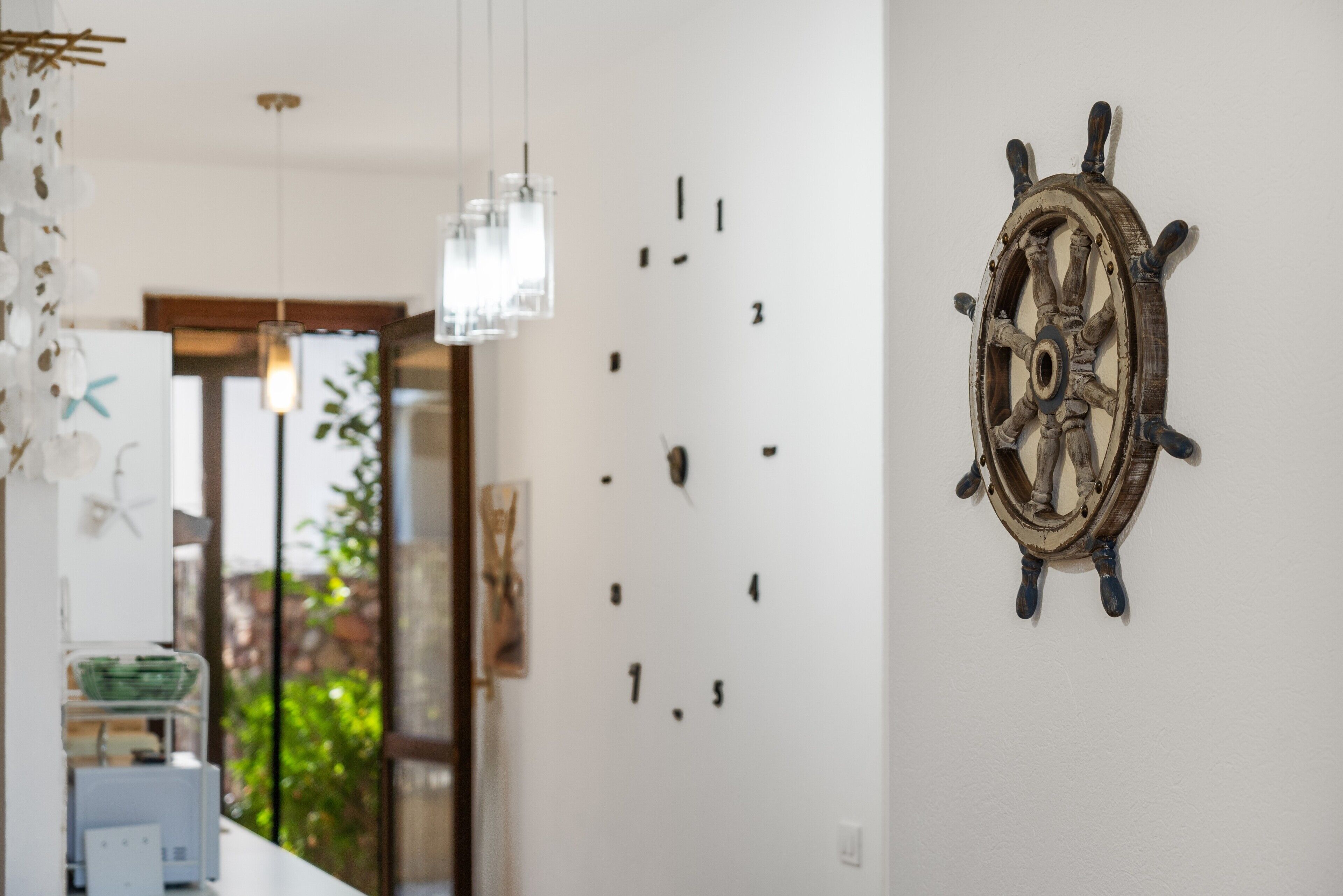 A room with a wall-mounted ship's wheel, a whiteboard with numbers, and a hanging light fixture.