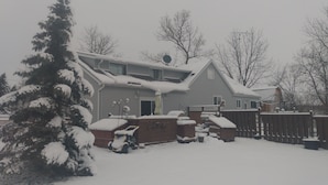 Une maison à deux étages, dont le toit et la cour sont recouverts de neige.