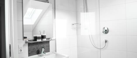 A modern bathroom with a white sink, mirror, and shower.