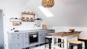 Eine moderne Küche mit grauen Schränken, einem Holztisch und Barhocker.