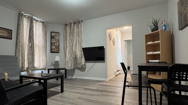 A modern living room with a sofa, a coffee table, and a TV mounted on the wall. - Serenity Suite - 2Br (Cornwall)
