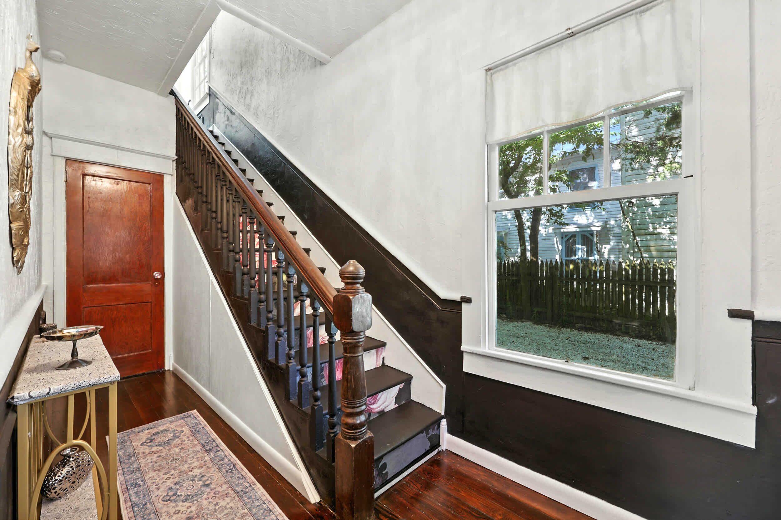 A staircase with dark wood railings and a wooden handrail, leading to a landing with a white door.