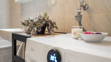 A modern bathroom with a digital shower control, a potted plant, and a bowl of fruit.