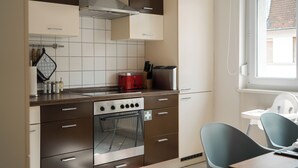 A modern kitchen with a built-in oven, a red toaster, and a stainless steel range hood.