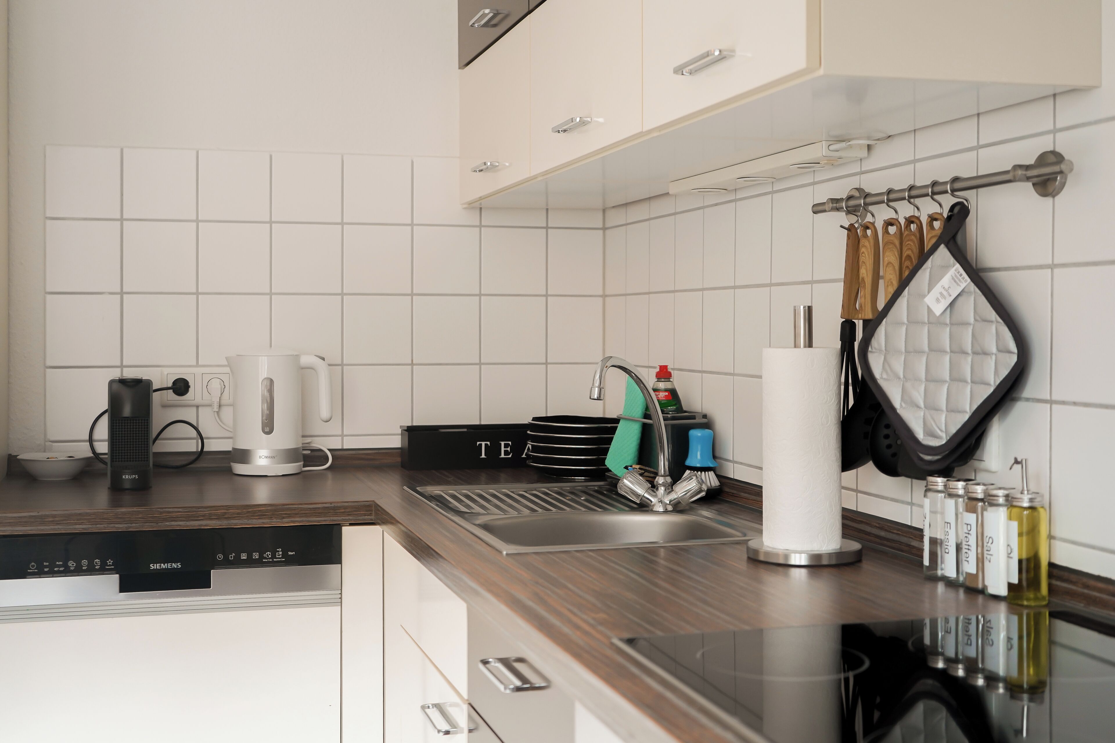 A modern kitchen with a Siemens dishwasher, a kettle, and a kettle holder on the counter.