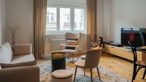 A modern living room with a sofa, armchairs, a coffee table, and a TV.