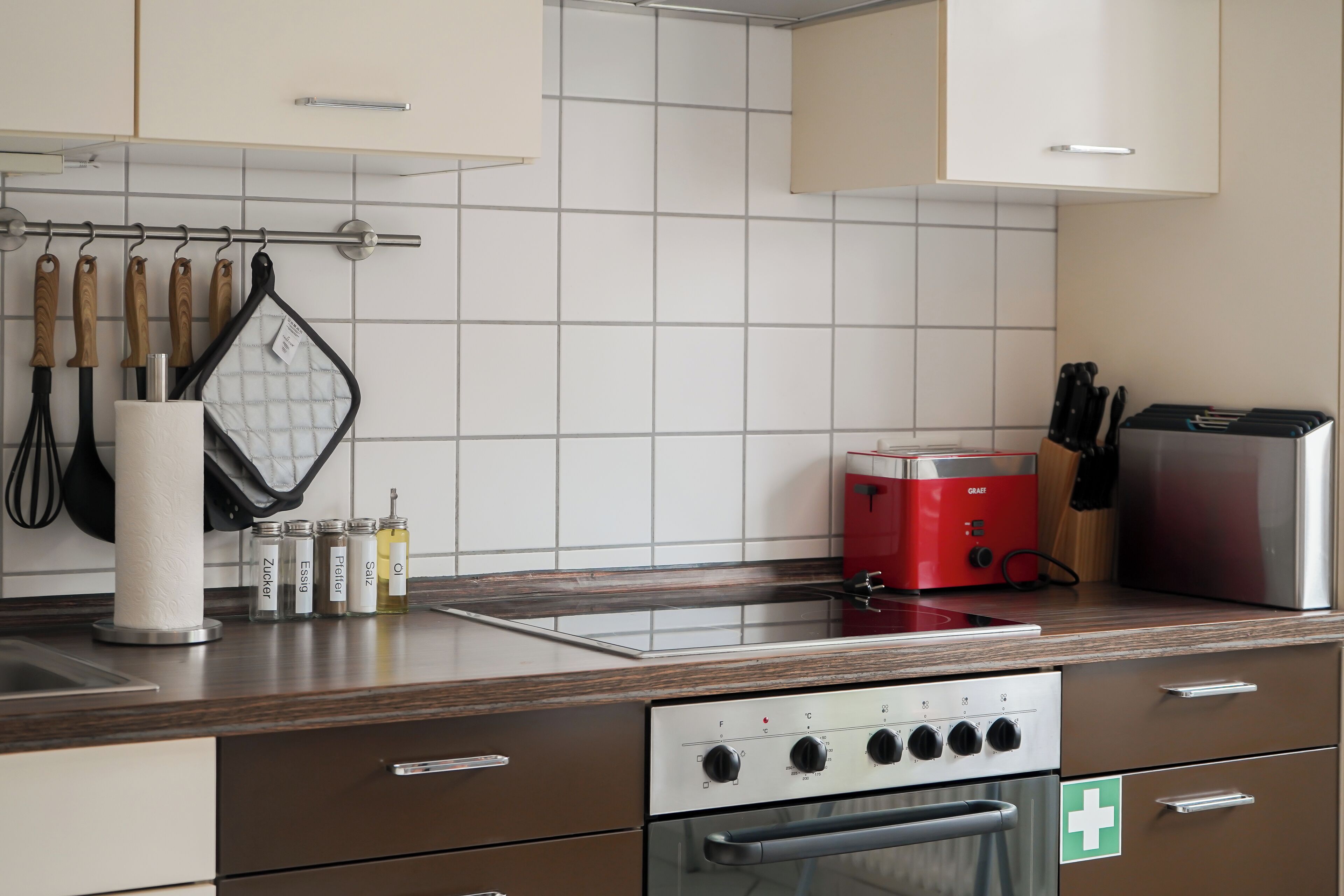 Een keuken met een roestvrijstalen oven, een rode toaster en diverse keukengerei.