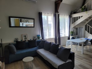 Un salon moderne avec un canapé, une table à manger et un escalier.