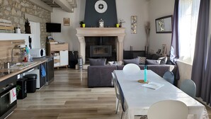 Una cocina moderna con pared de piedra, chimenea y comedor con mesa y sillas.