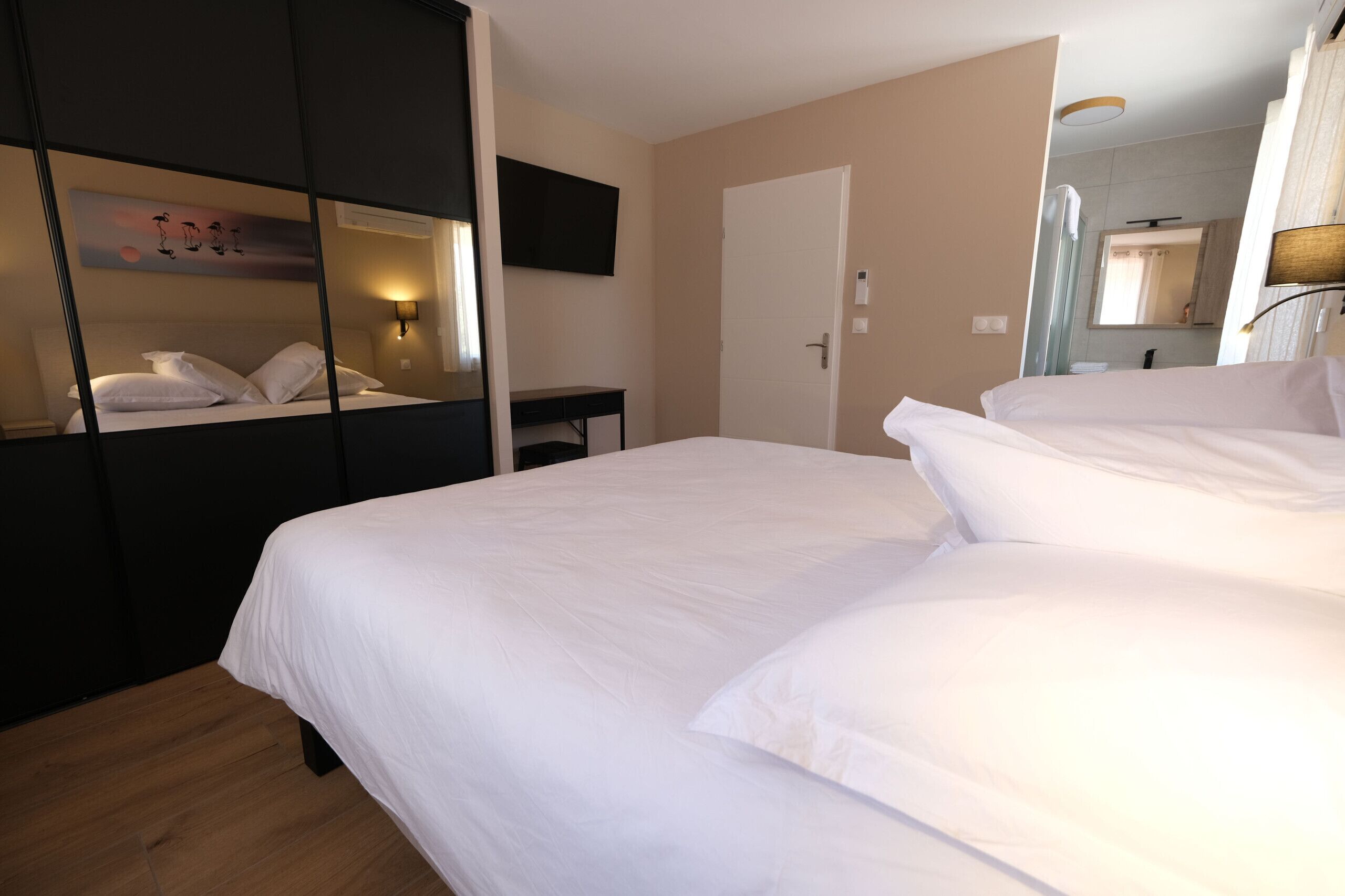 Una habitación de hotel con una cama grande, un escritorio, un televisor de pantalla plana montado en la pared y un espejo sobre la puerta.