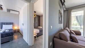 Habitació d'hotel moderna amb un llit, un sofà, una taula petita amb una làmpada i vista a l'exterior.