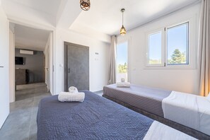 A modern hotel room with two beds, a large window, and a view of the outdoors.