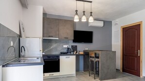 Una cuina moderna amb forn integrat, rentapelats i taulell. Hi ha una zona de bar amb tamborets i un televisor de pantalla plana fixat a la paret.