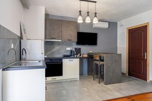 Une cuisine moderne équipée d’un four encastré, d’un évier et d’un plan de travail. On y trouve également un coin bar avec des tabourets et un téléviseur à écran plat fixé au mur.