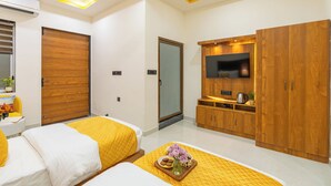 Una camera da letto moderna con due letti, un armadio in legno, una televisione e un piccolo tavolo con un vassoio di snack.