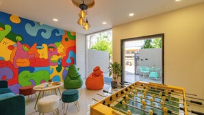 Una stanza dai colori vivaci con un tavolo da calcio, divani colorati e un grande murale astratto sulla parete.