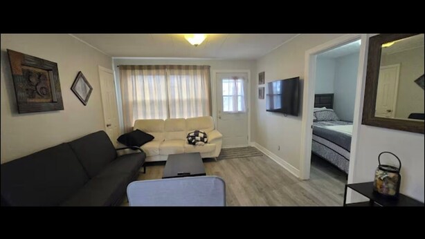 A compact living space with a sofa, a small table, a bed, and a television. - Cozy 2-Bedroom Apartment (Cornwall)
