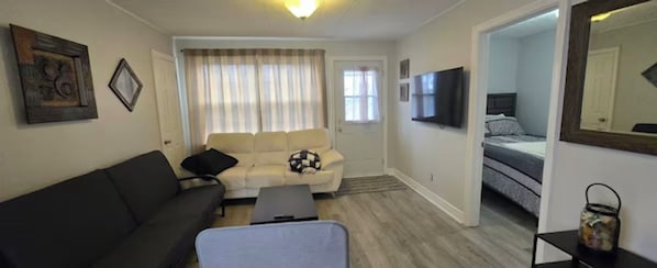 A compact living space with a sofa, a small table, a bed, and a television.