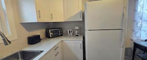 A compact kitchen with a sink, a toaster, a coffee maker, and a refrigerator.