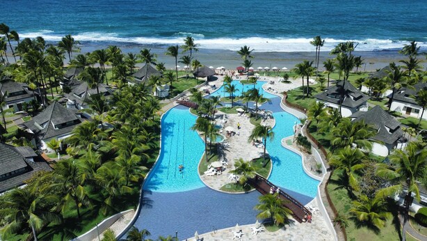 A resort with a large swimming pool, palm trees, and a beach view. - Beach Class Resort 1305 by La Playa  (Ipojuca)