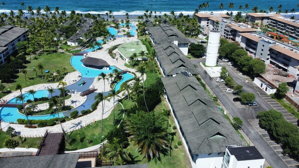 Un resort con varias piscinas, una zona de playa y un estacionamiento.