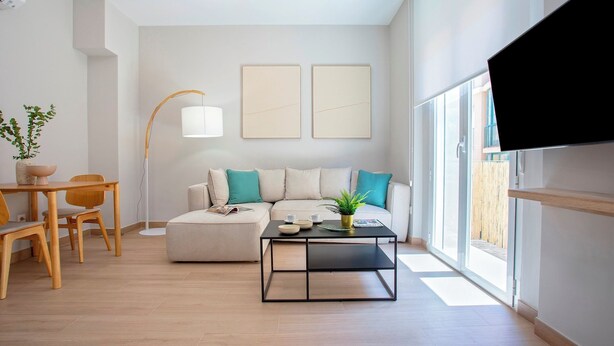 A modern living room with a sofa, coffee table, and dining area. - Genteel Home Trinidad Grund B (Málaga)