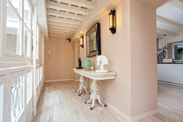A hallway with a white railing, a white console table with decorative items, and a wall-mounted mirror.