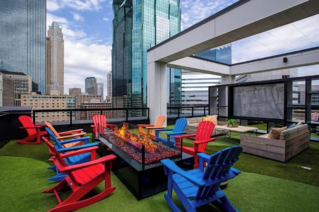 Eine Dachterrasse mit Feuerstelle, Sitzgelegenheit und Blick auf die Stadt.