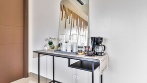A modern hotel room with a minimalist design, featuring a large mirror, a small table with a coffee maker, and a decorative vase. - Bayshore  Captain Quarters 50% Off| Bayview & Pool (Parañaque)