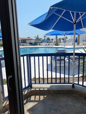 Un espace piscine agrémenté de parasols bleus, de chaises longues et offrant une vue dégagée sur la piscine.