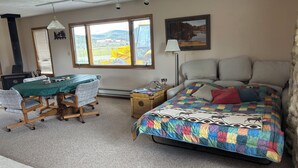 A bedroom with a bed, a desk, a chair, a lamp, and a window.