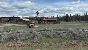 A rural property with multiple buildings, a fenced area, and a yellow vehicle.