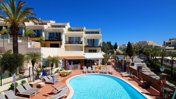 A hotel with a swimming pool, sun loungers, and a restaurant.