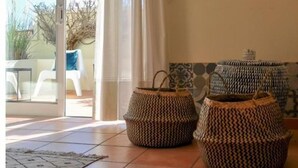 A room with a sliding glass door leading to an outdoor area, a patterned wall hanging, and two woven ottomans.