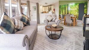 Ein modernes Wohnzimmer mit einer Couch, Sesseln, einem Couchtisch und einem Essbereich mit Tisch und Stühlen.