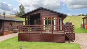 Eine Holzhütte mit Veranda, großen Fenstern und einer überdachten Sitzgelegenheit im Freien.