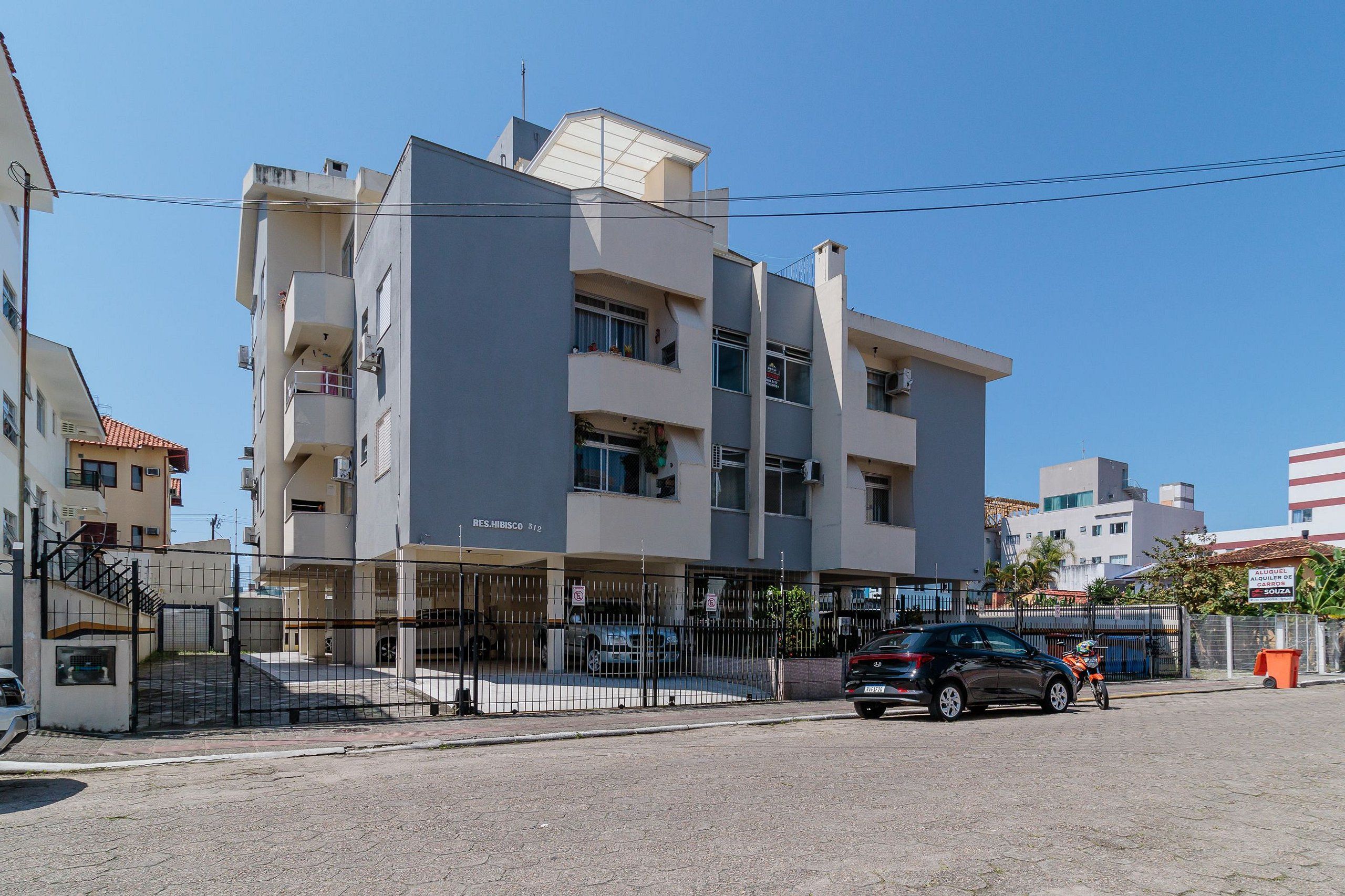 A multi-story building with a flat facade, balconies, and a gated entrance.