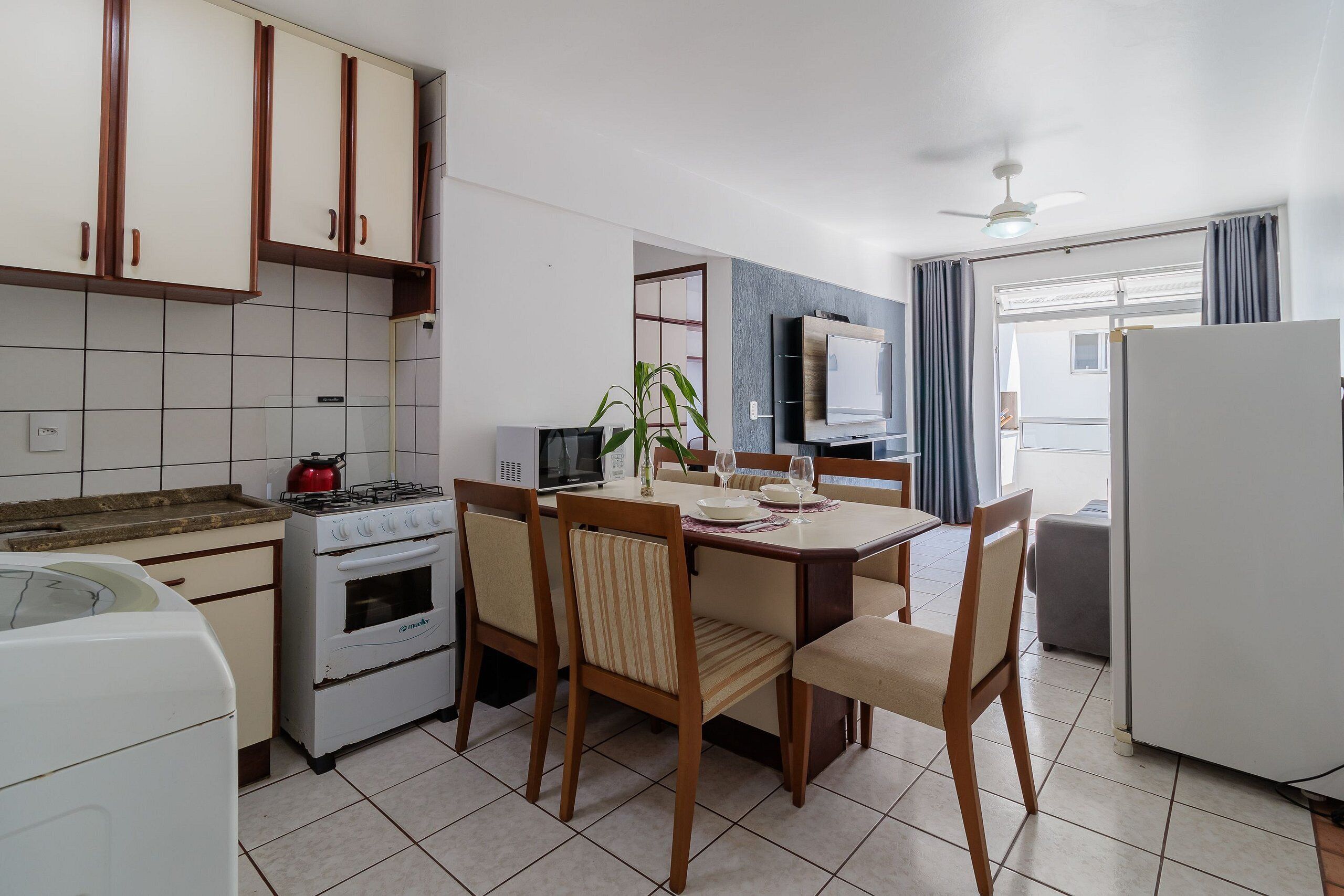 Una cocina compacta con comedor, estufa, refrigerador y ventilador de techo.