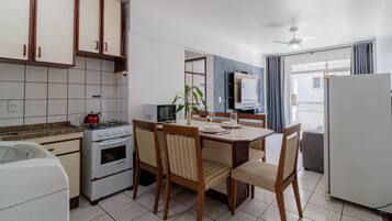 Una cocina compacta con comedor, estufa, refrigerador y ventilador de techo.