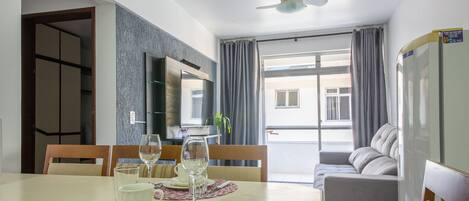 Un comedor con una mesa preparada para dos, un sofá y un televisor.