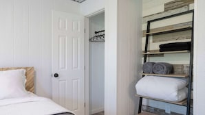 A bedroom with a bed, a white door, and a built-in shelf with rolled towels and pillows. - Bison View Secluded Cabin for 6 w/ Hot Tub on Wildlife Sanctuary (Johnson City)