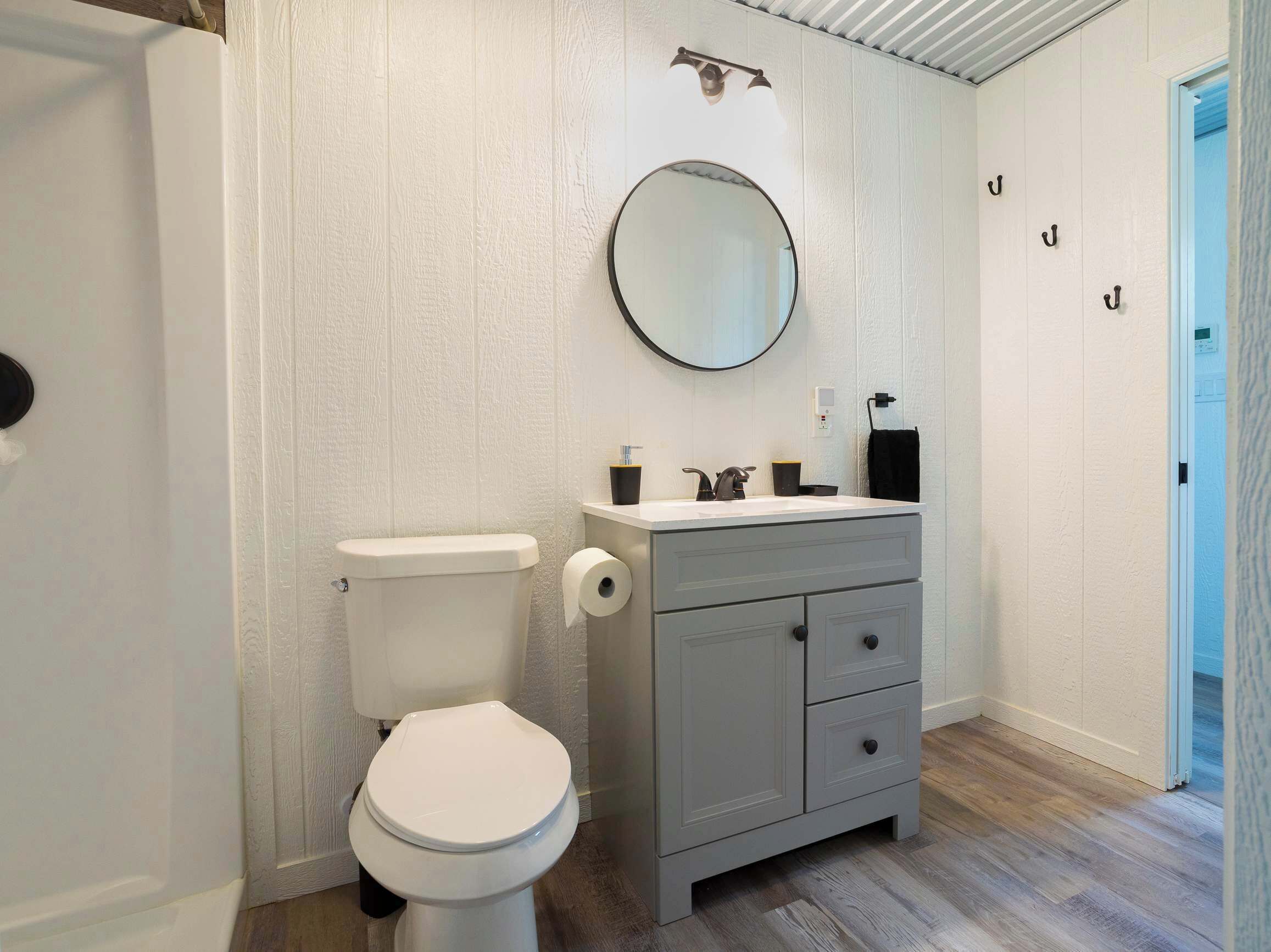 A bathroom with a toilet, a sink with a mirror above it, and a cabinet with drawers.