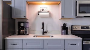 A kitchen with grey cabinets, a stainless steel sink, a coffee maker, a microwave, and a toaster. - Bison View Secluded Cabin for 6 w/ Hot Tub on Wildlife Sanctuary (Johnson City)