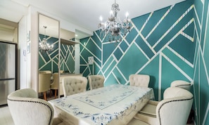 A dining room with a geometric-patterned wall, a chandelier, and a table with a floral tablecloth. - Apt With Barbecue Near the Beach Rgn0203 (Florianópolis)