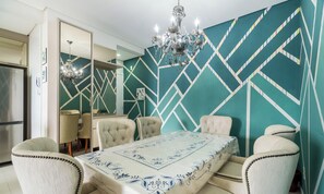 Ein Esszimmer mit Tisch für sechs Personen, einer Kristallleuchtre und einer Wand mit geometrischem Muster.