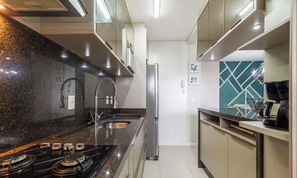 A modern kitchen with a gas stove, stainless steel sink, and a refrigerator. - Apt With Barbecue Near the Beach Rgn0203 (Florianópolis)