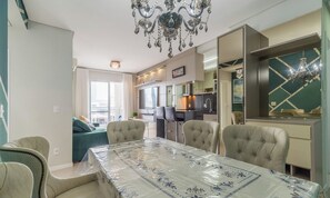 A modern living room with a dining table, chairs, a sofa, and a kitchen area. - Apt With Barbecue Near the Beach Rgn0203 (Florianópolis)