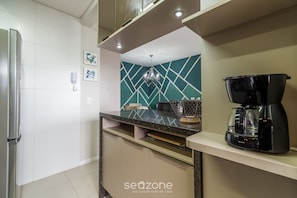 A modern kitchen with a built-in coffee maker, a microwave, and a refrigerator. - Apt With Barbecue Near the Beach Rgn0203 (Florianópolis)