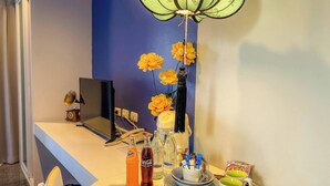 A hotel room with a desk, a computer, a telephone, and a decorative vase with yellow flowers. - Room-hotel With Balcony in Phukettown (Phuket)