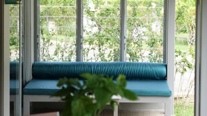 A covered patio with a blue cushioned bench, a round wooden table, and a hanging light fixture. - 2 Bedroom Neer Phuket Airport (Sa Khu)
